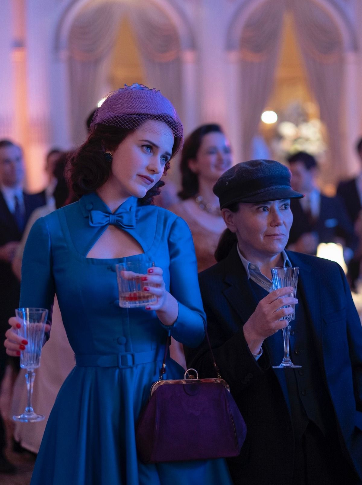 https://www.womaninrevolt.com/content/images/2022/03/Midge-and-Susie-double-fisting-drinks-at-Shys-wedding-How-to-Chew-Quietly-and-Influence-People-The-Marvelous-Mrs-Maisel.jpeg